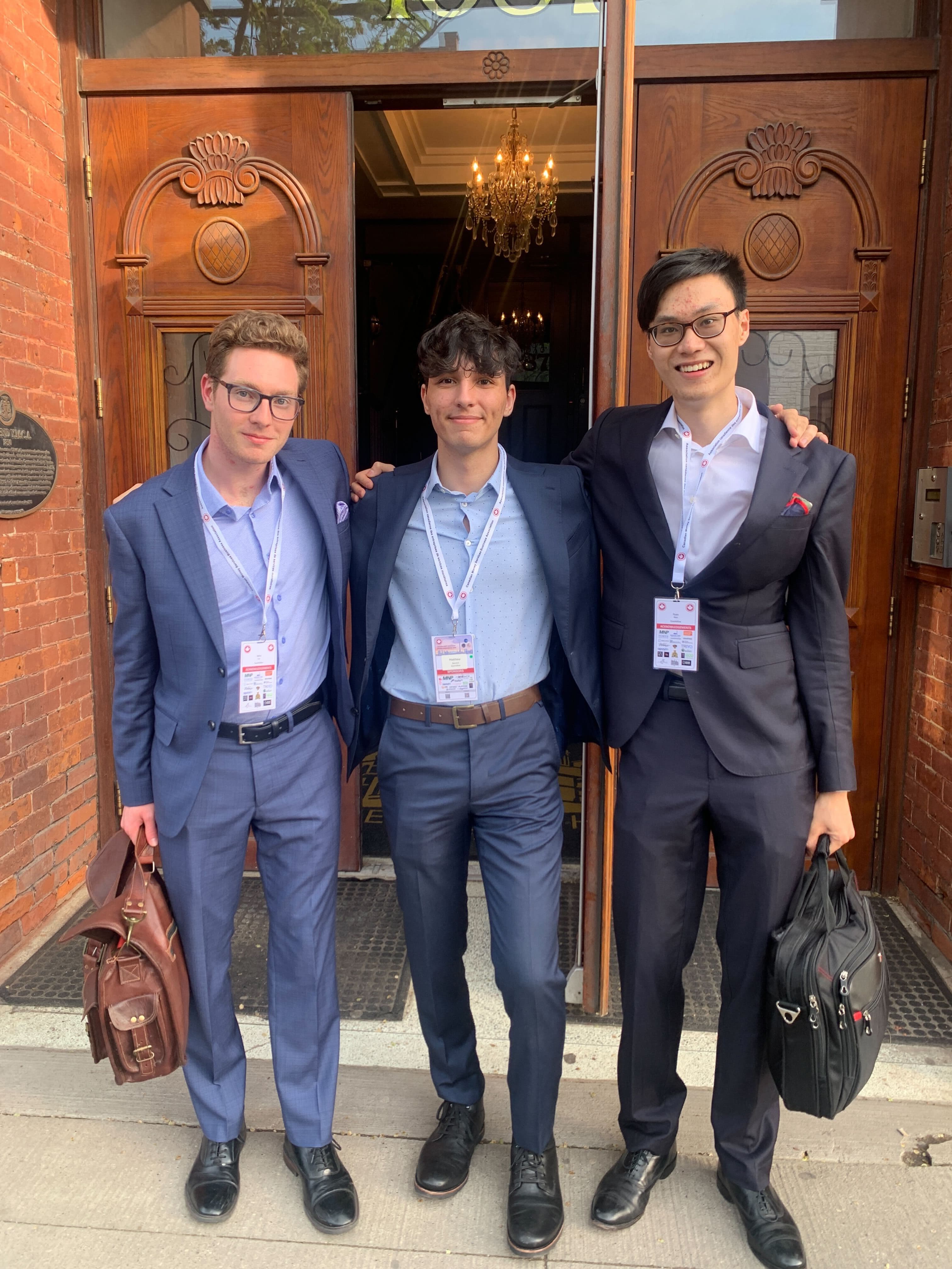 Three members of the Quantoflow team in suits outside a Canadian MSB compliance conference